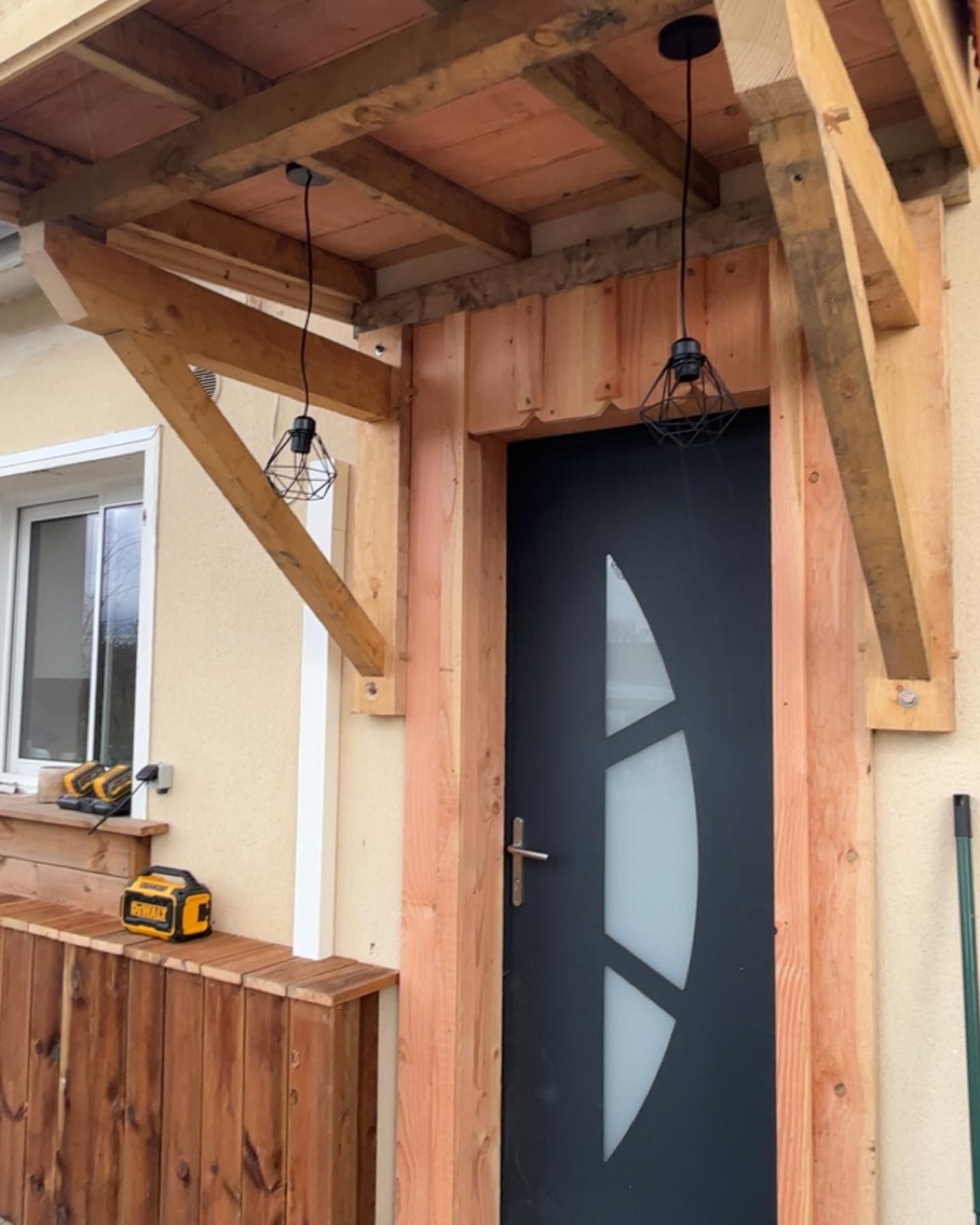 Bardage en bois autour d'une porte d'entrée en PVC