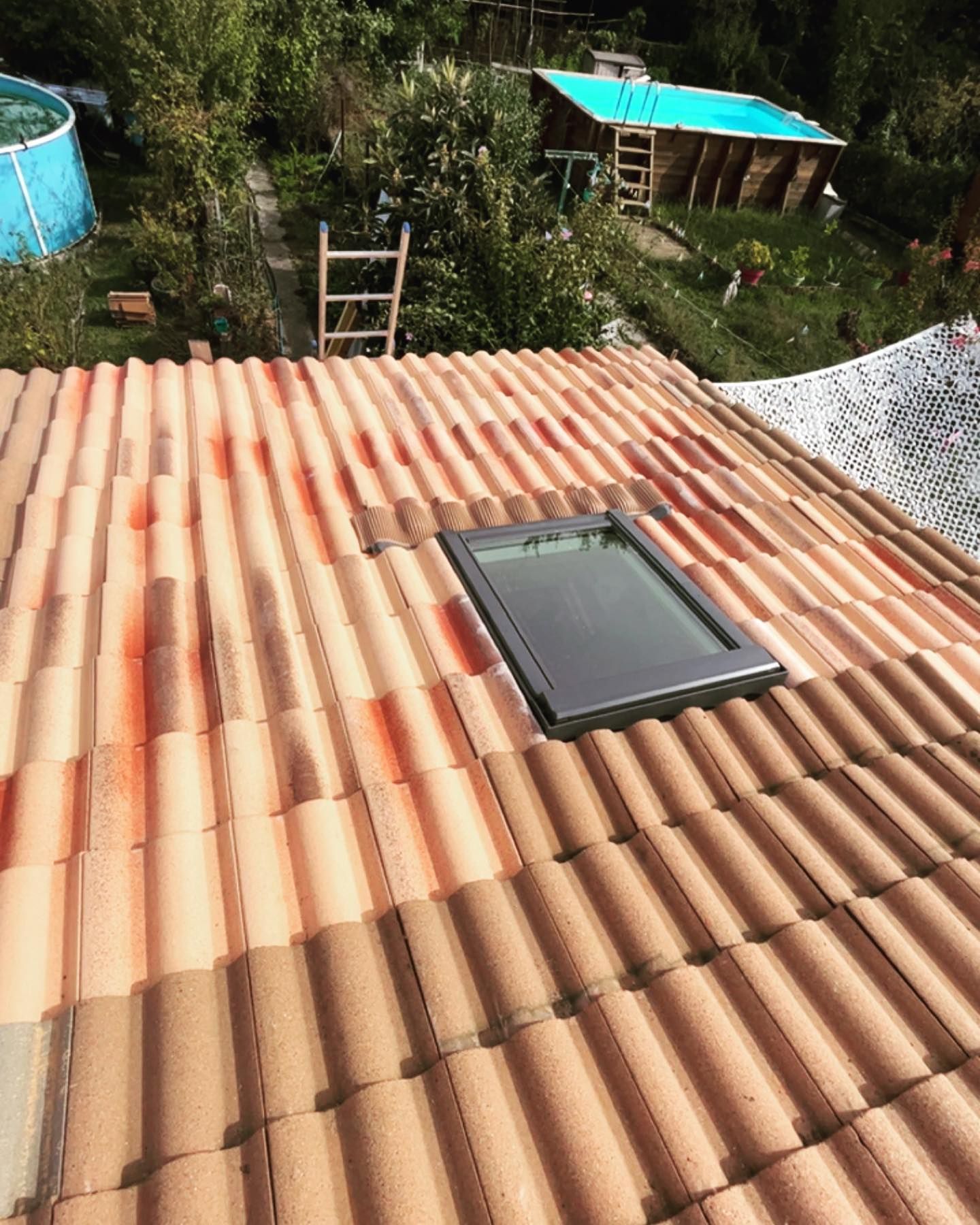 Toiture en tuiles avec une fenêtre de toit et une échelle