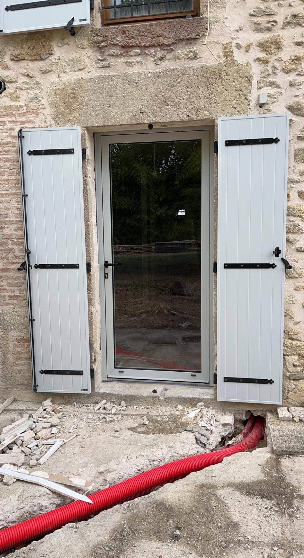 Pose de volets battants blancs avec une porte vitrée