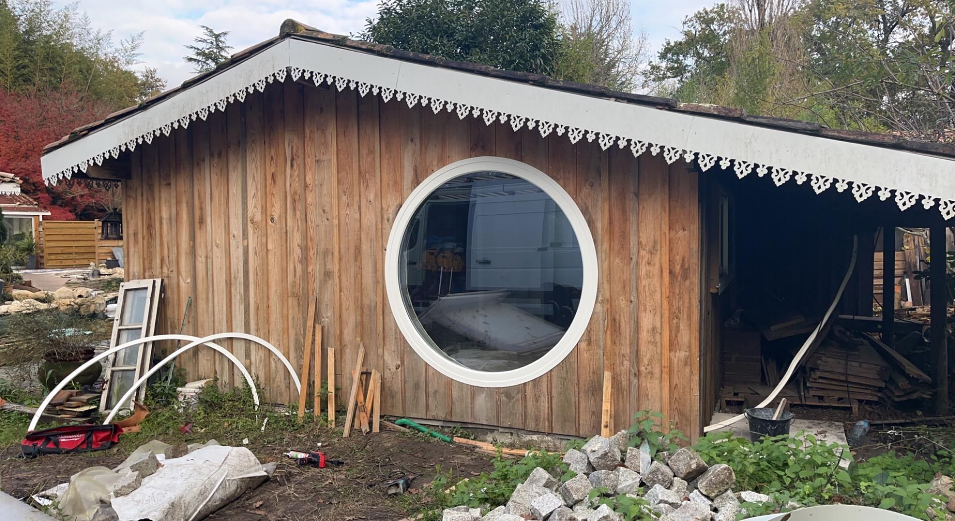 Façade en bois avec une fenêtre circulaire et des soffites ouvragés