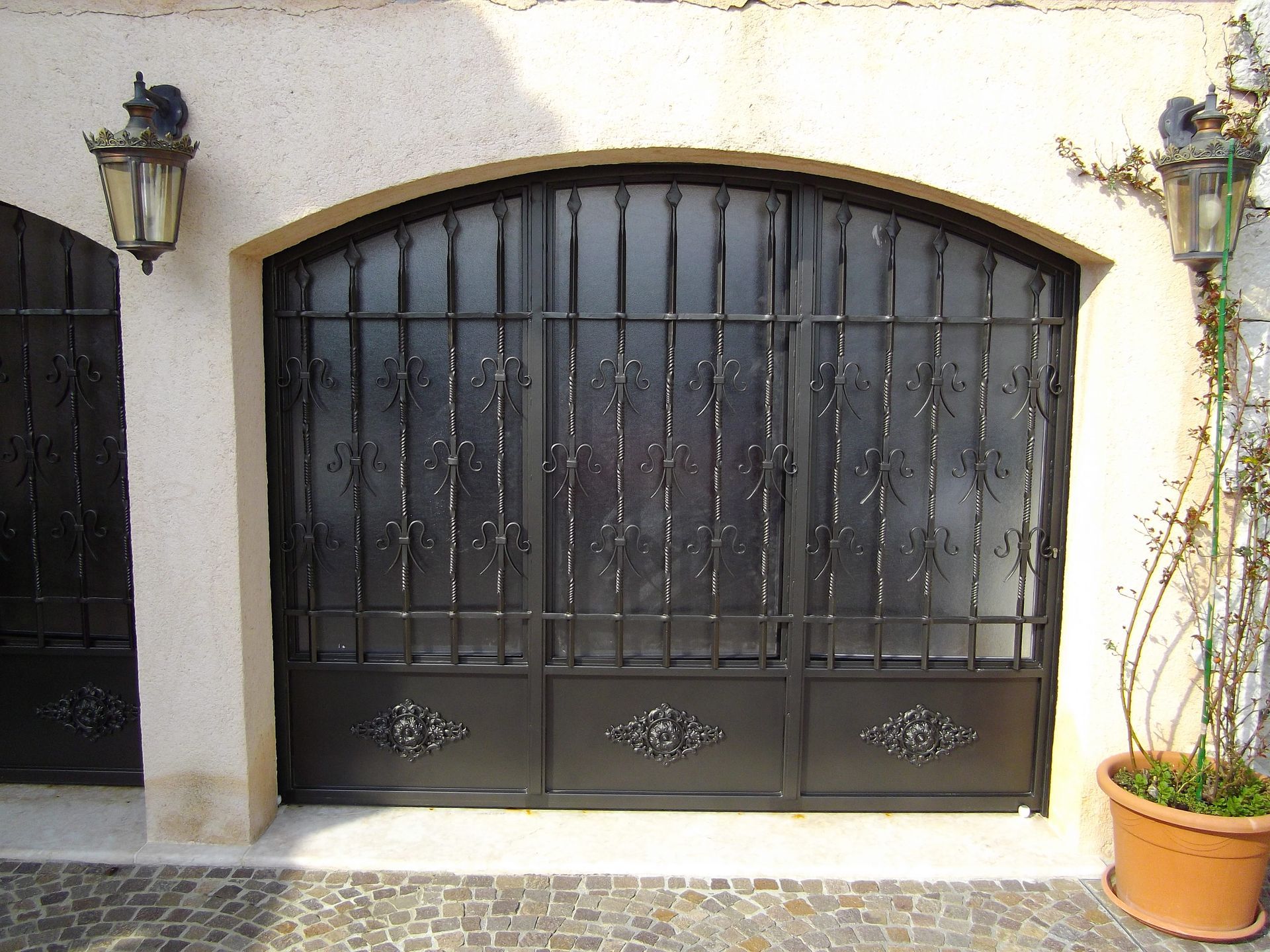 Portes de garage en fer forgé noir avec ornements décoratifs, porte cintrée.