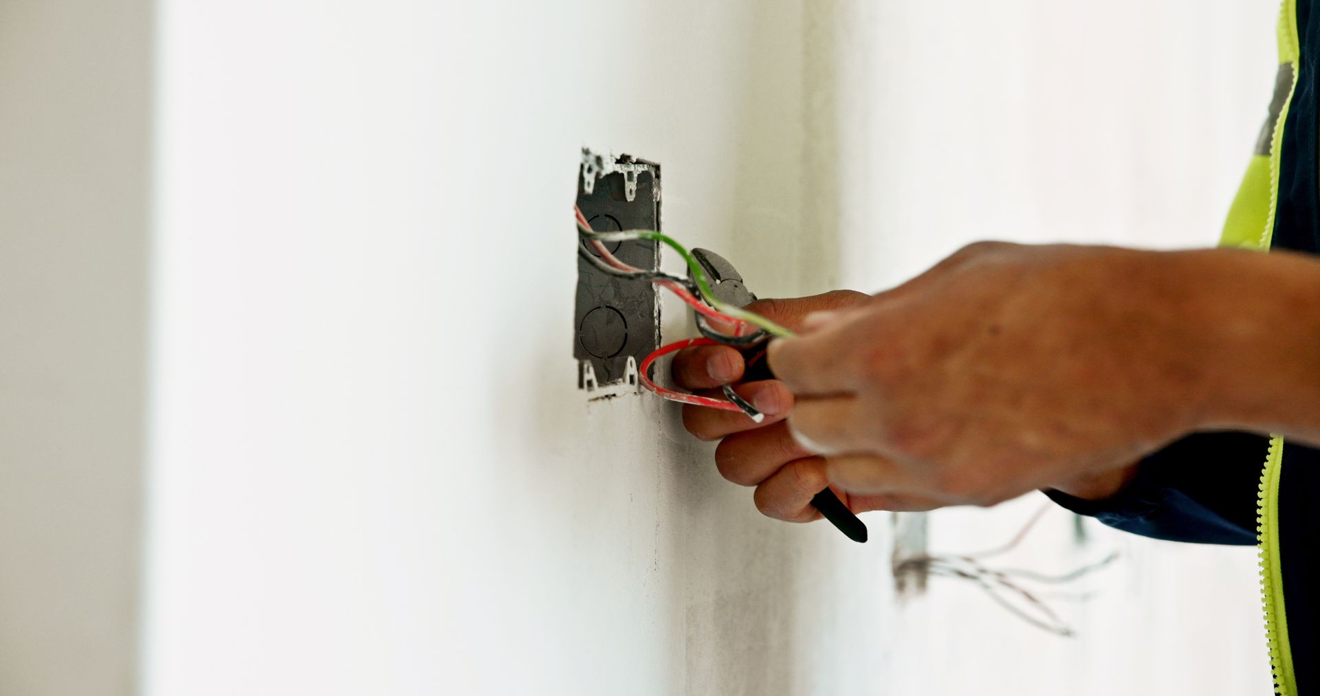 Électricien manipulant des fils électriques sortant d'un mur