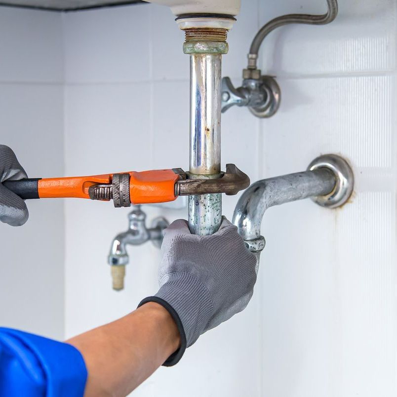 Plombier resserrant le tuyau d'un lavabo