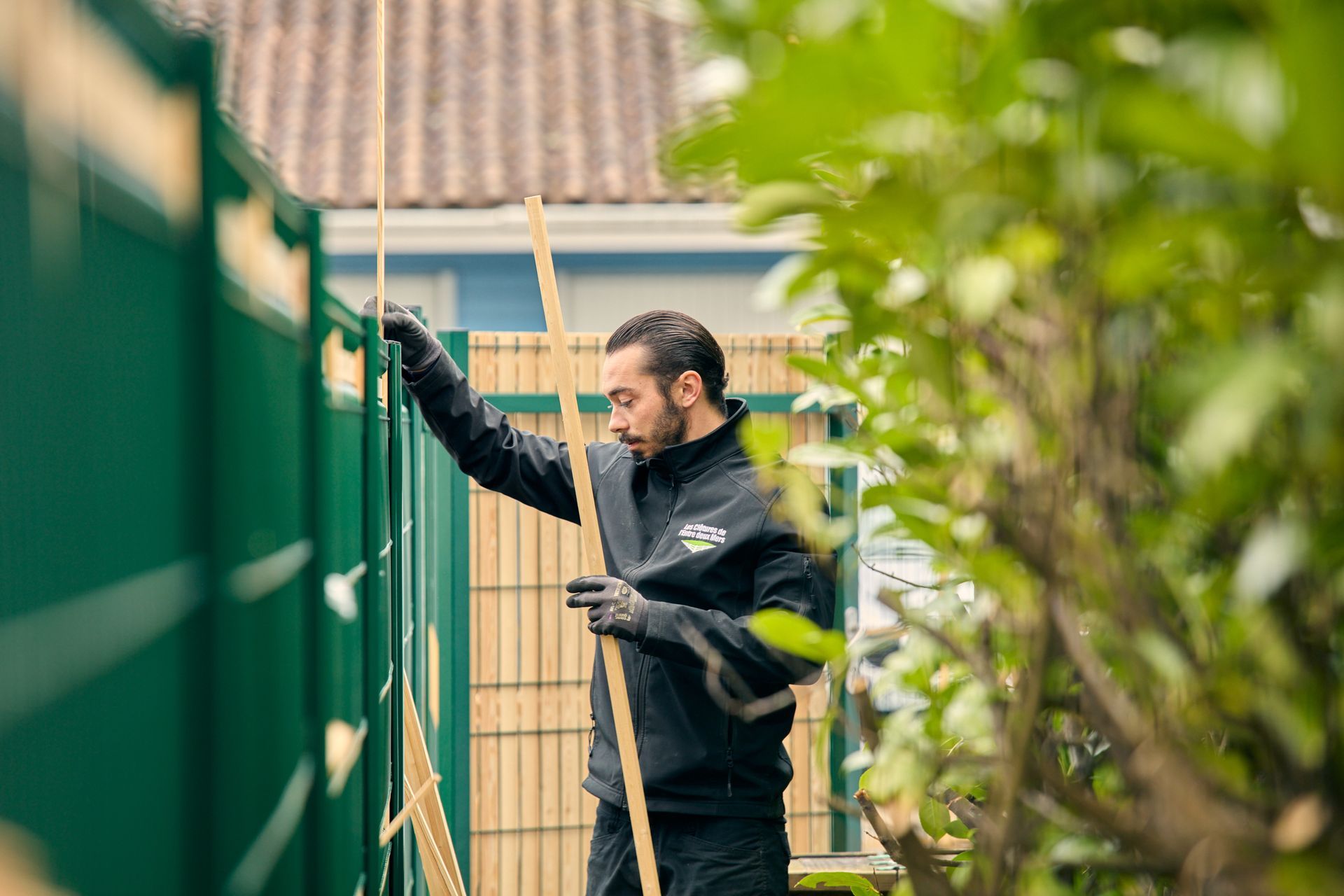 Artisan de l'entreprise Les clôtures de l'Entre deux Mers réalisant la pose d'une clôture lors d'un chantier