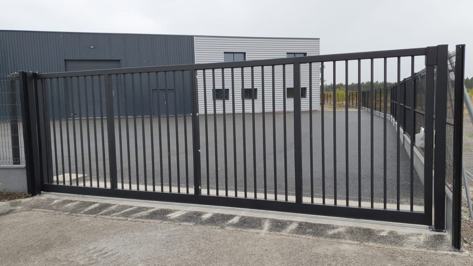 Portail coulissant en acier moderne devant une entreprise