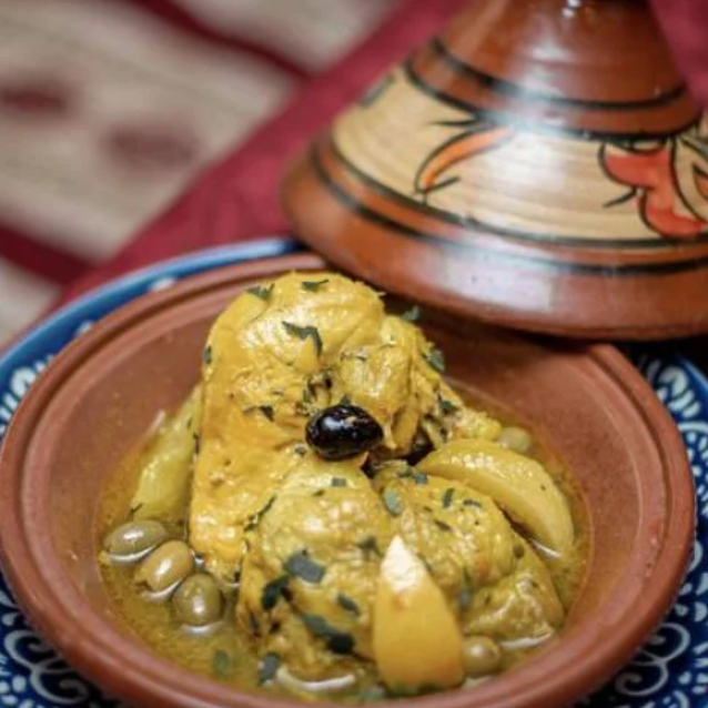 Tajine au poulet, olives et citron confit servi dans un bol en terre cuite brune