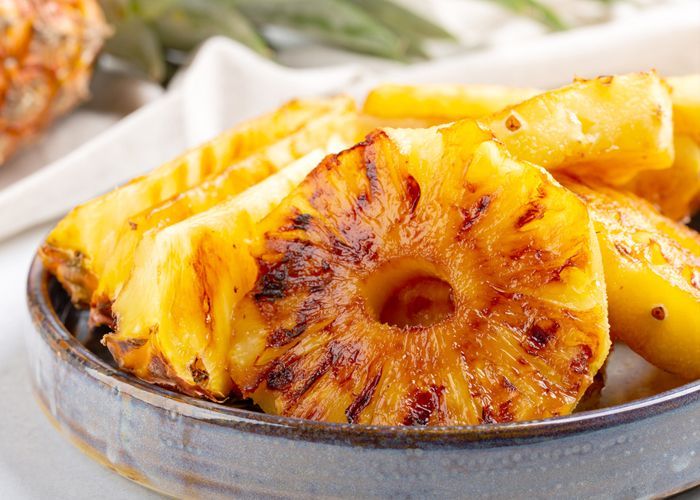 Tranches d'ananas grillées dans un bol, dorées et caramélisées sur les bords.