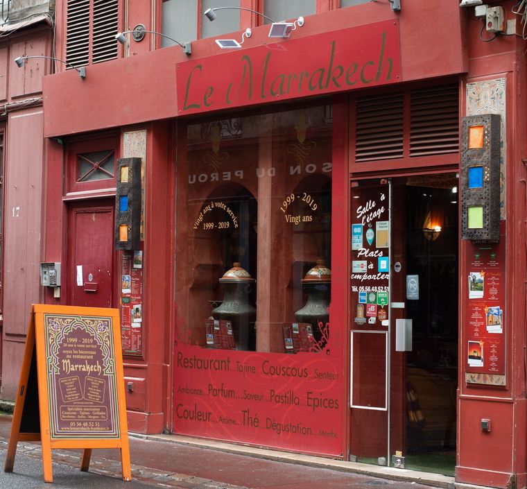 Façade rouge avec menu à la craie et porte ouverte sur une rue de la ville