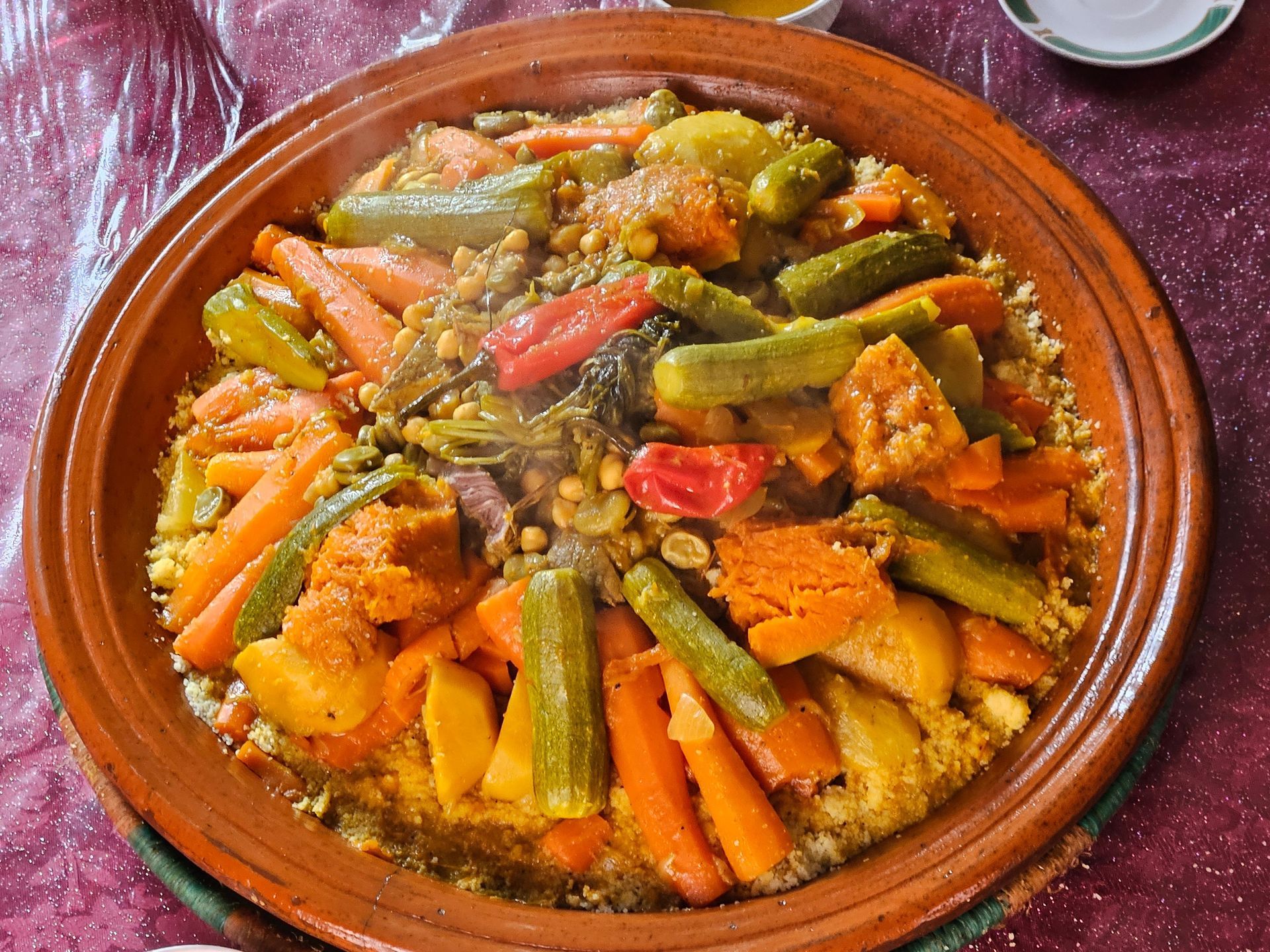 Couscous aux légumes colorés dans un tajine en terre cuite sur une nappe