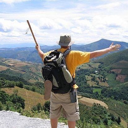 Un excursionista con mochila y bastón de trekking se encuentra en un mirador de montaña