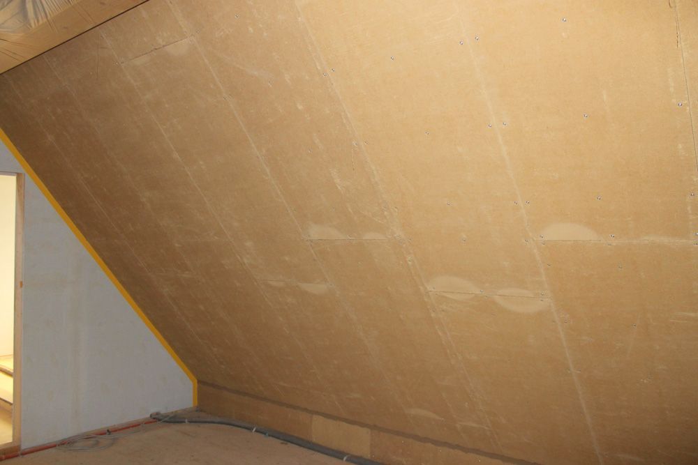 Ein Raum mit schräger Decke und einer Holzwand.