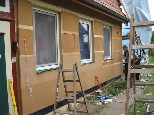 Ein Mann arbeitet an der Seite eines Hauses.