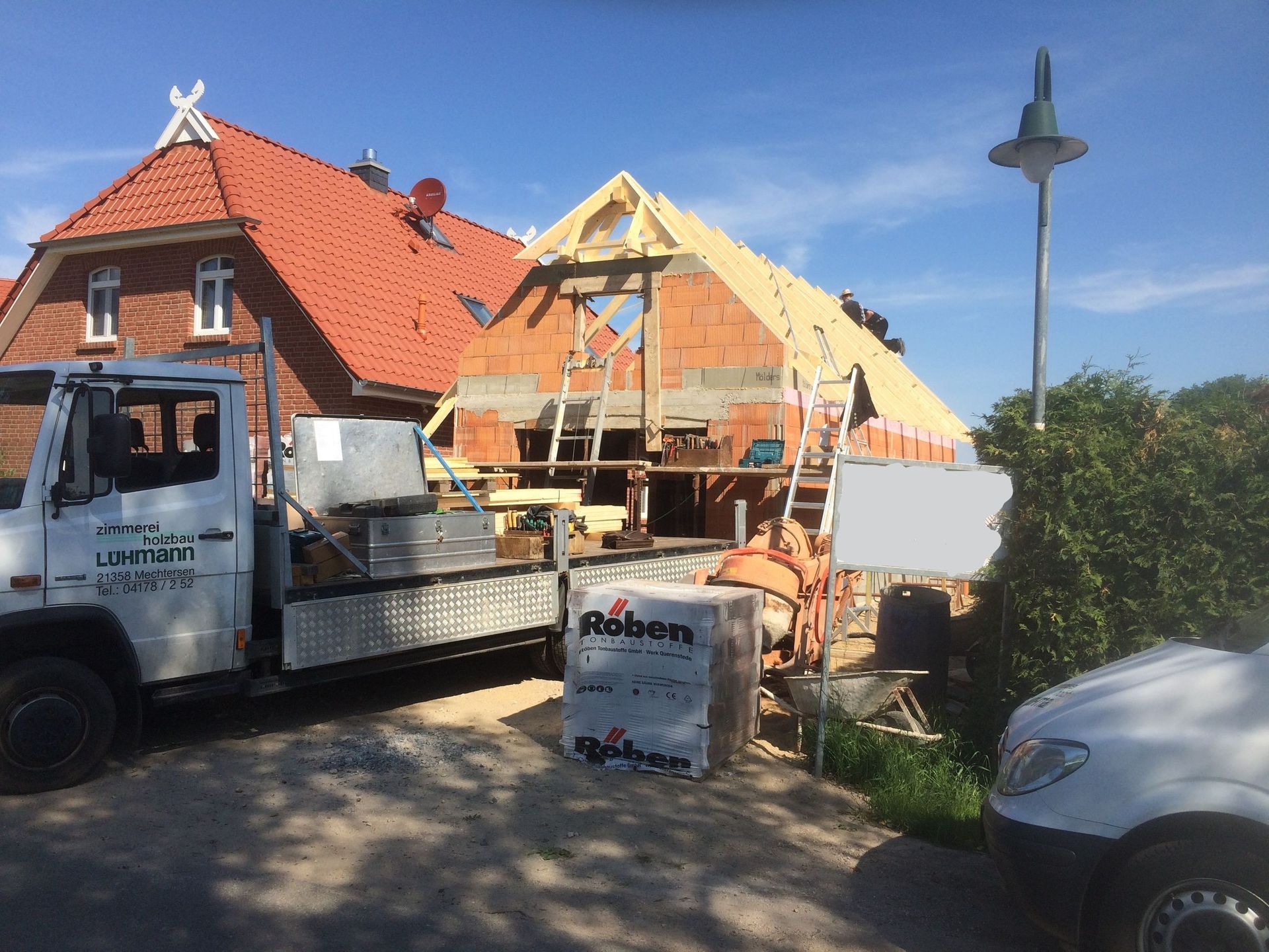 Ein weißer Lastwagen parkt vor einem im Bau befindlichen Haus.