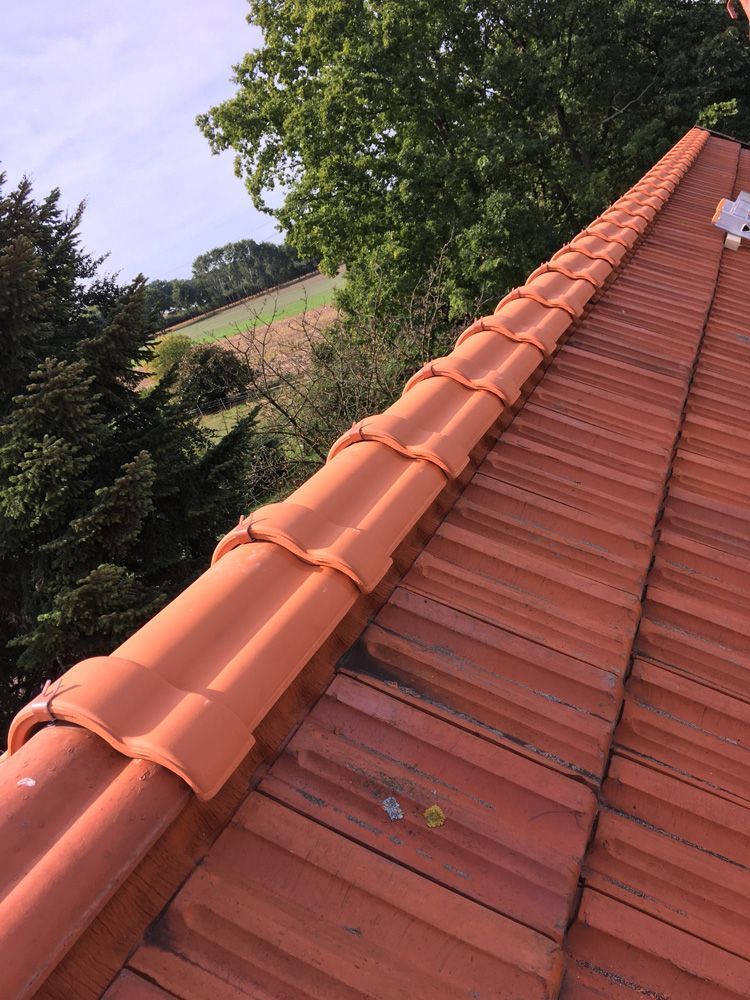 Ein Dach mit vielen Ziegeln darauf und Bäumen im Hintergrund.