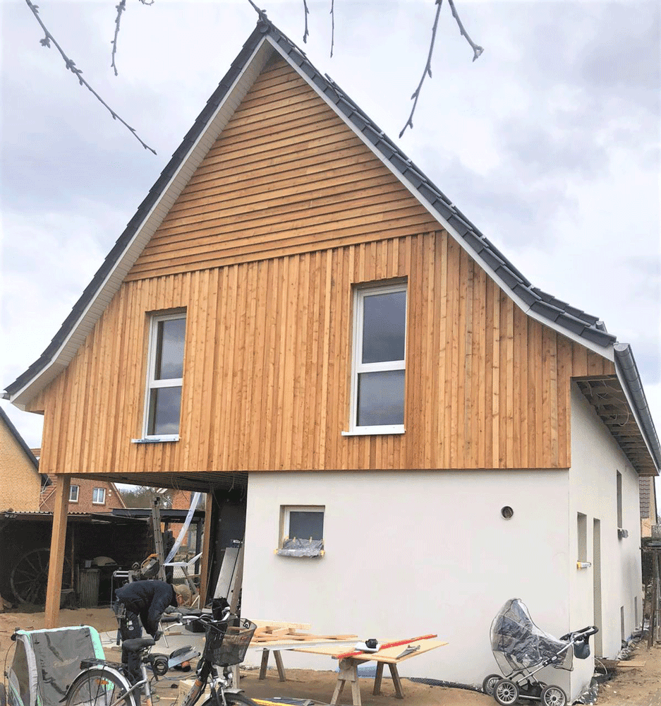 Ein weißes Haus mit Holzverkleidung und einem Fahrrad davor.