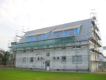 Es wird ein großes weißes Gebäude mit Gerüst darum herum errichtet.