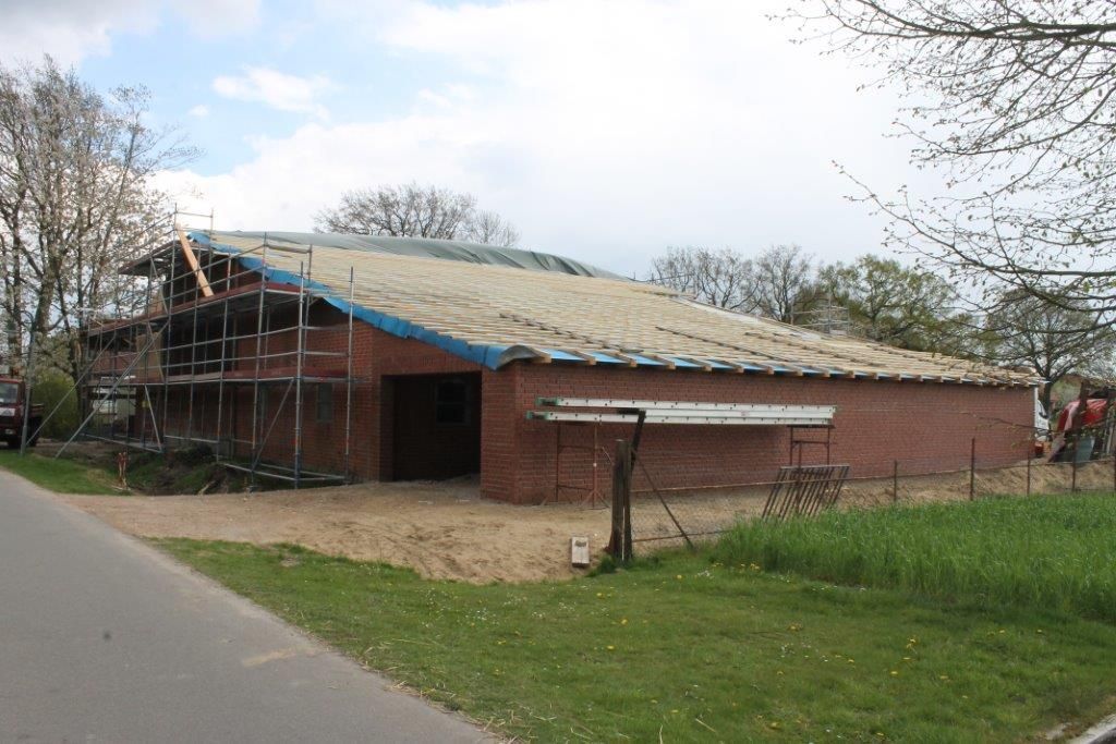 Neben einer Straße wird ein großes Backsteingebäude errichtet.