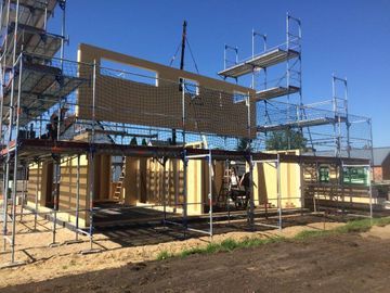 Mit Gerüst und Kran wird ein Gebäude errichtet.