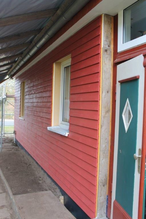 Ein rotes Haus mit einer grünen Tür und einem grünen Fenster