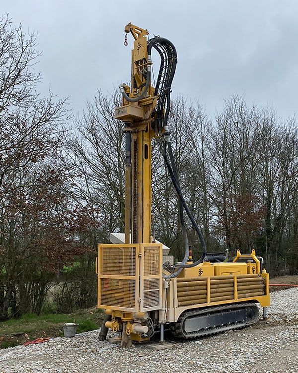 Machine de forage jaune sur un terrain de cailloux