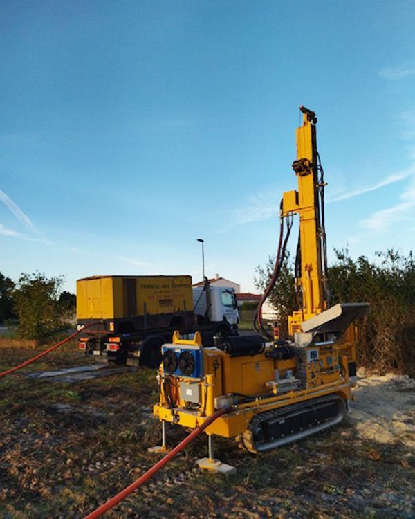 Véhicule motorisé jaune de forage devant un camion