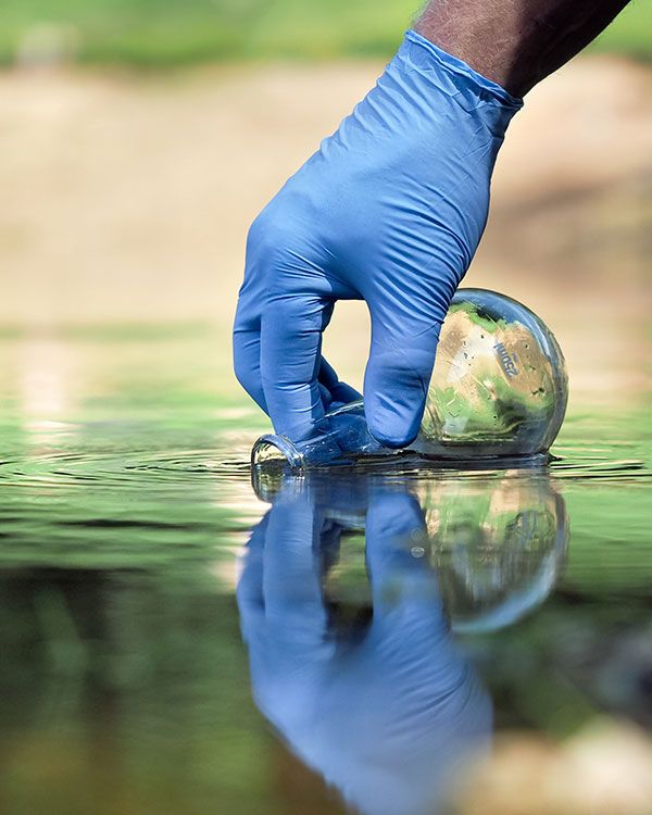 Main récoltant de l'eau dans un ballon en verre