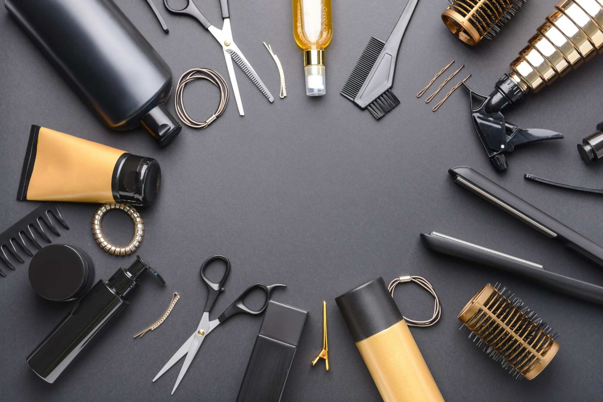 Herramientas y accesorios para peinar el cabello dispuestos sobre un fondo gris, incluyendo cepillos, peines, tijeras.