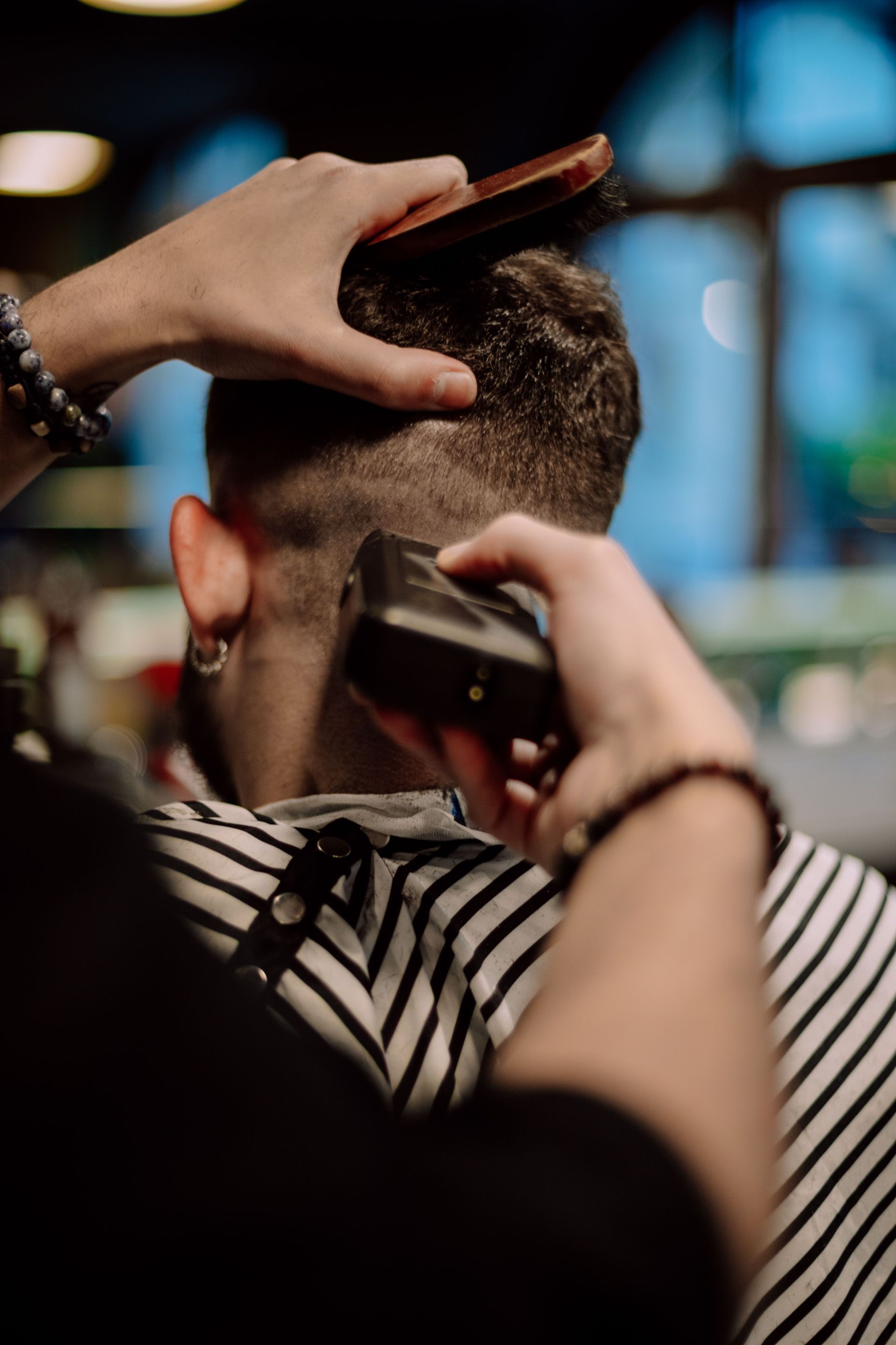 Un barbero le recorta la barba a un cliente en un salón de belleza, mientras el cliente está recostado en una silla.