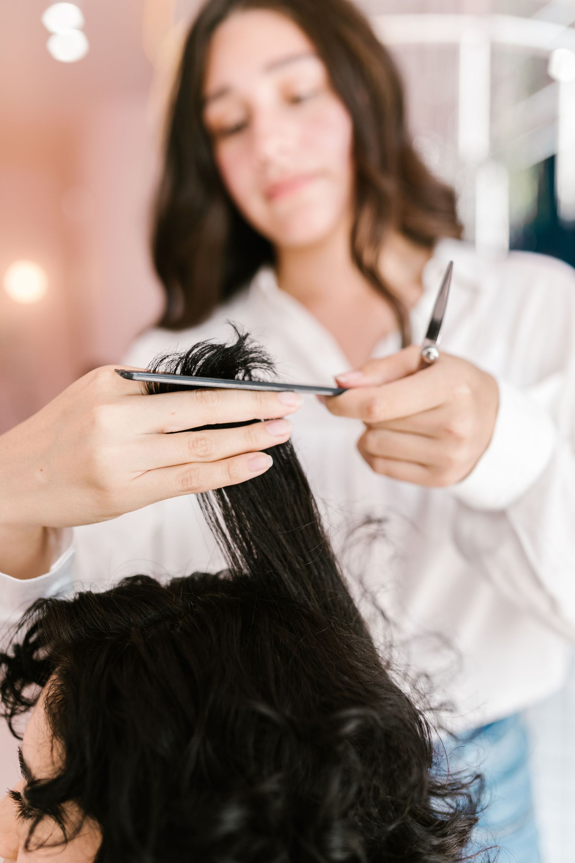 Peluquera recortando cabello rizado con tijeras en un salón de belleza.