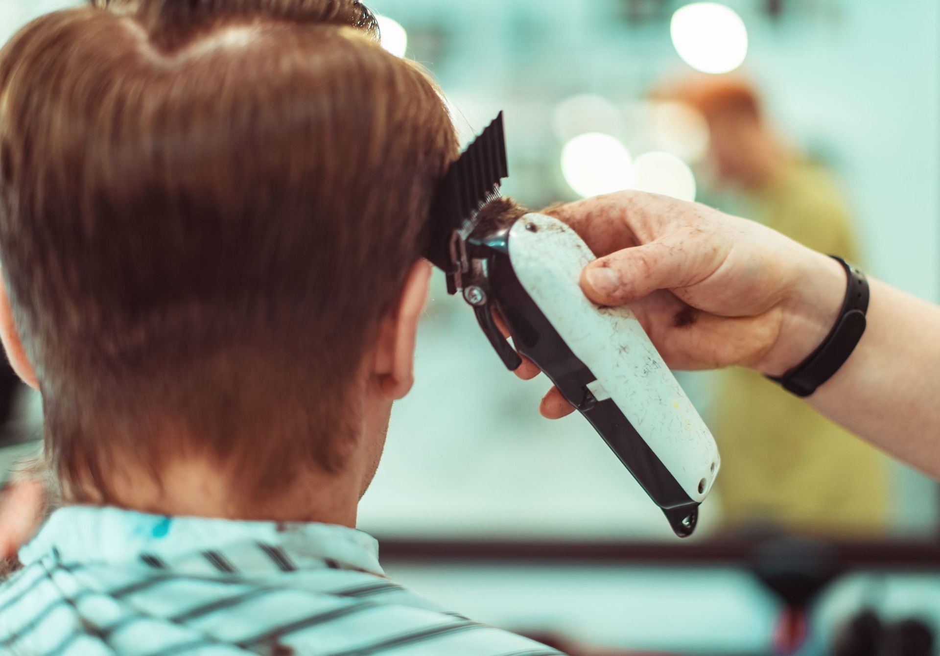 Peluquero recortando el pelo corto de una persona con una maquinilla en un salón de belleza.