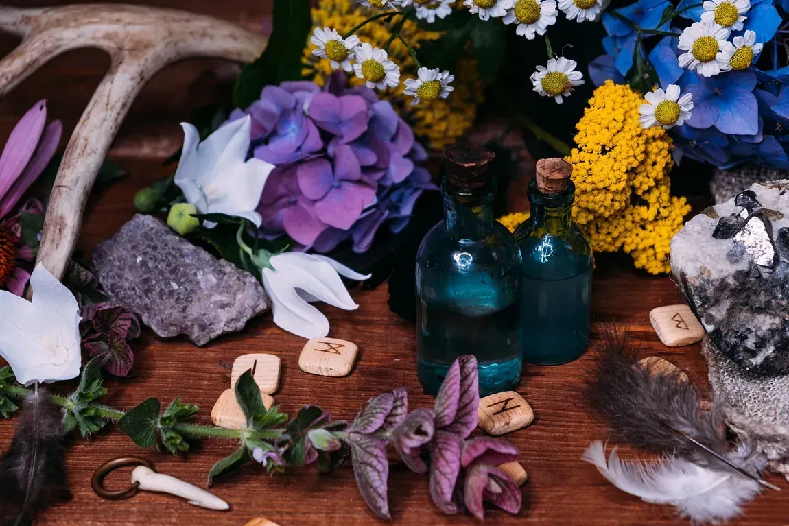 Una mesa de madera cubierta con flores, cristales, plumas y astas.