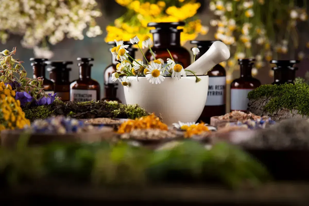 Un mortero lleno de hierbas y flores sobre una mesa.