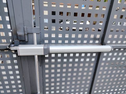Abrepuertas de garaje gris, con la parte inferior negra y un brazo de riel metálico