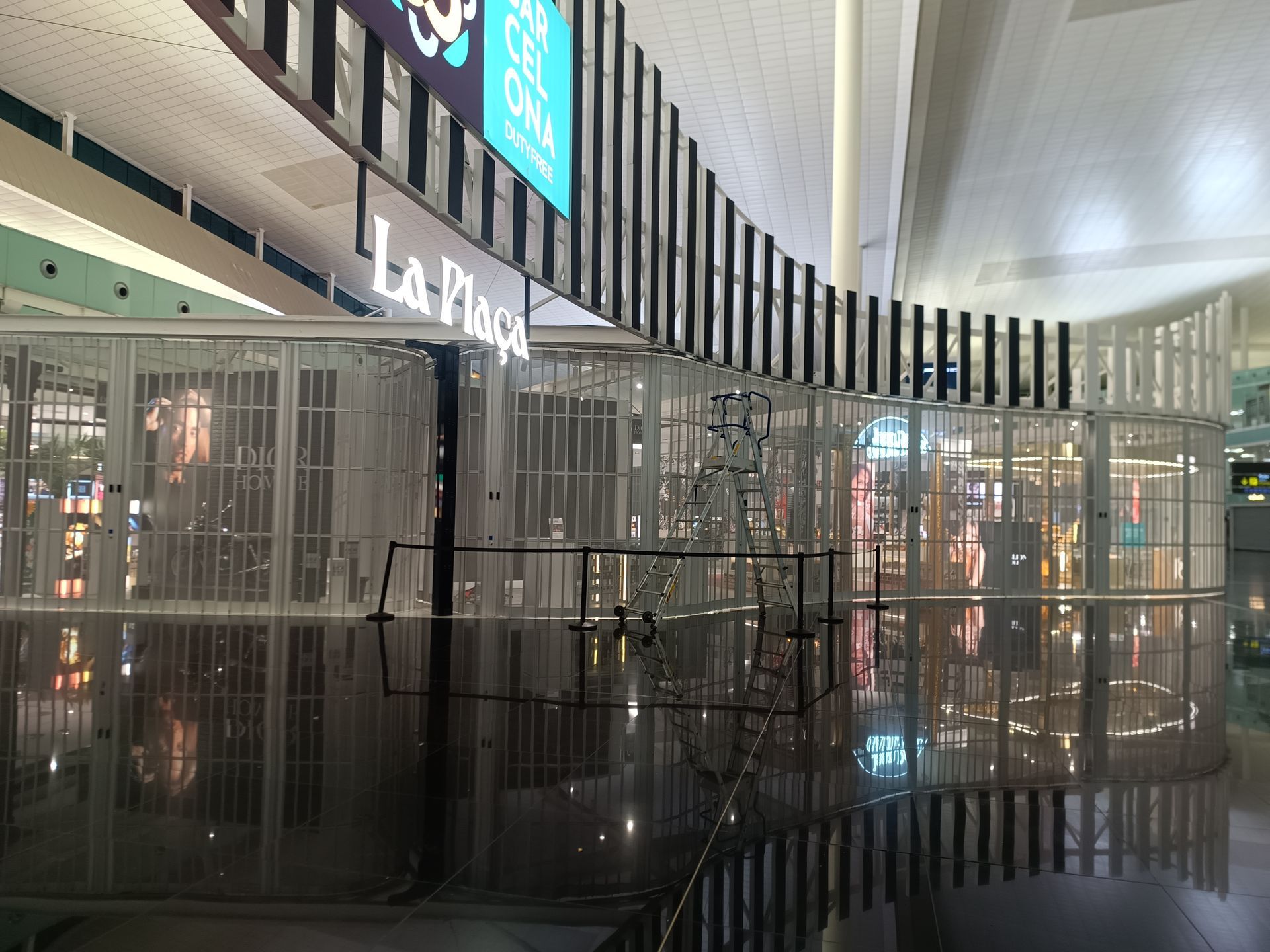 Pasillo interior de un centro comercial con una estructura metálica negra y varios locales, entre ellos uno con un letrero