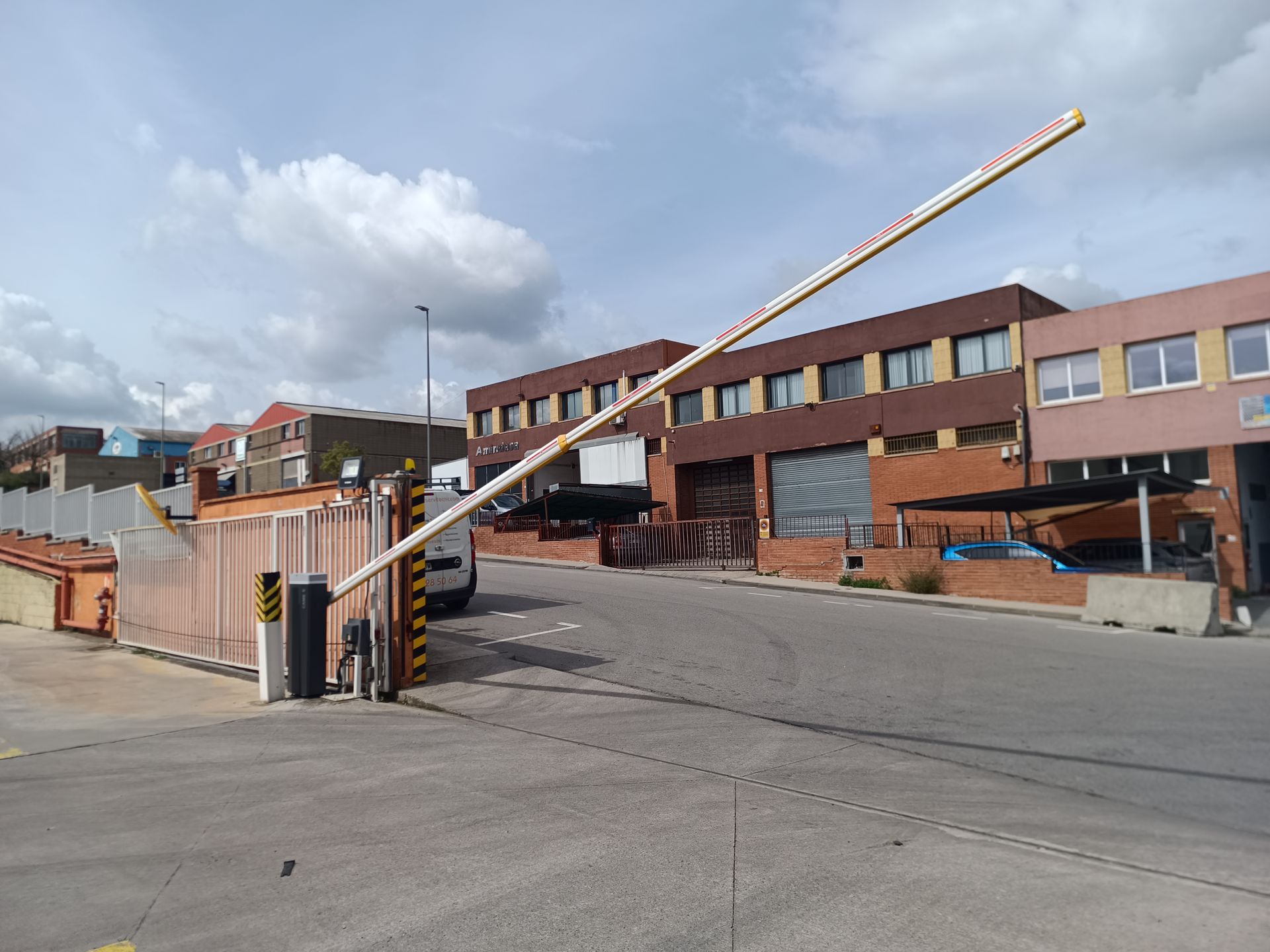 Subiendo la barrera de acceso a la entrada de un edificio industrial de ladrillo bajo un cielo nublado