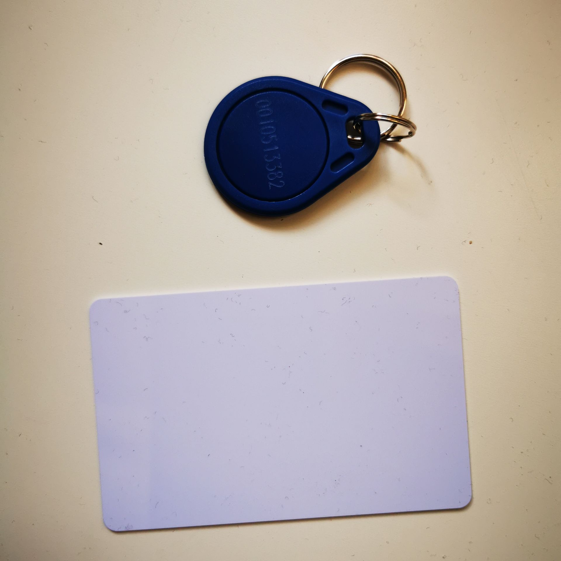 Llavero azul encima de una tarjeta blanca en blanco sobre una superficie beige