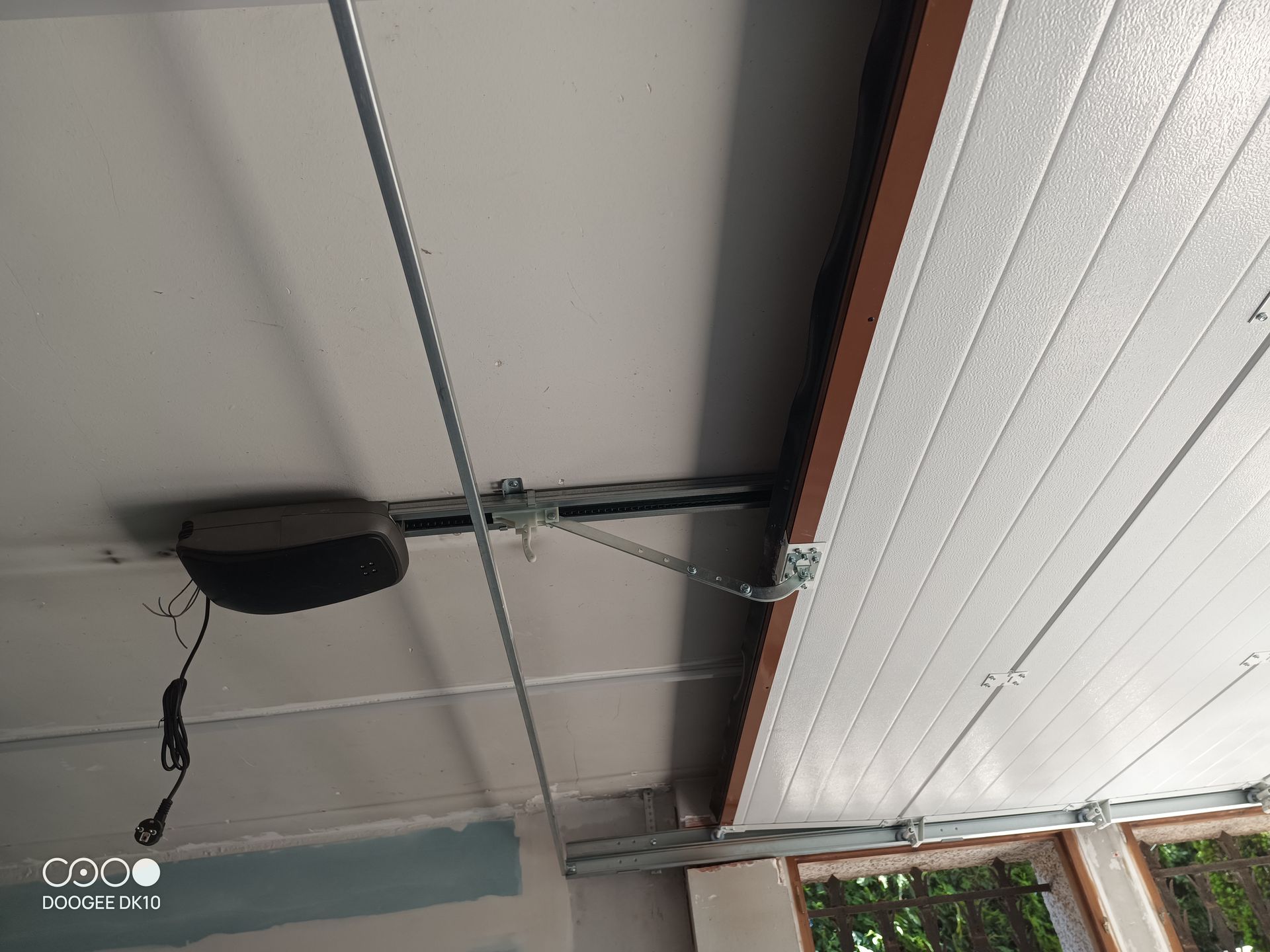 Techo del garaje con un panel parcialmente abierto, cables a la vista y una lámpara colgante.
