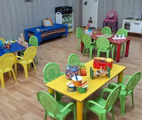 Un aula con mesas, sillas y juguetes sobre ellas.