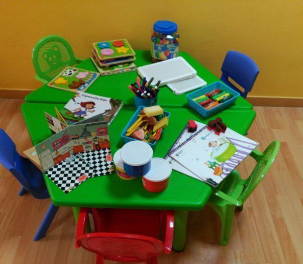 Una mesa verde con libros y juguetes encima.