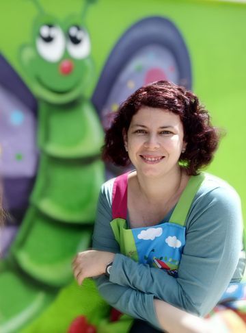 Una mujer está parada frente a un mural de una oruga verde.