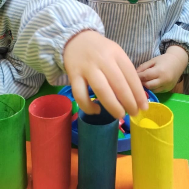 Un niño está jugando con rollos de papel higiénico de colores.