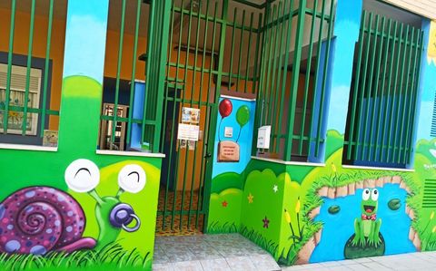 Un edificio con un mural de un caracol y una rana en el costado.