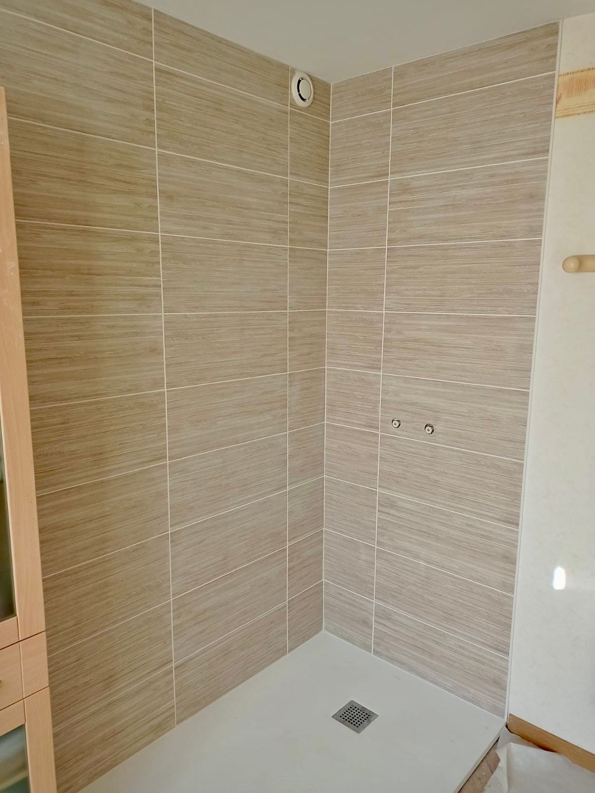 Une douche d'angle à l'italienne avec des carreaux muraux beiges imitation bois et un receveur de douche