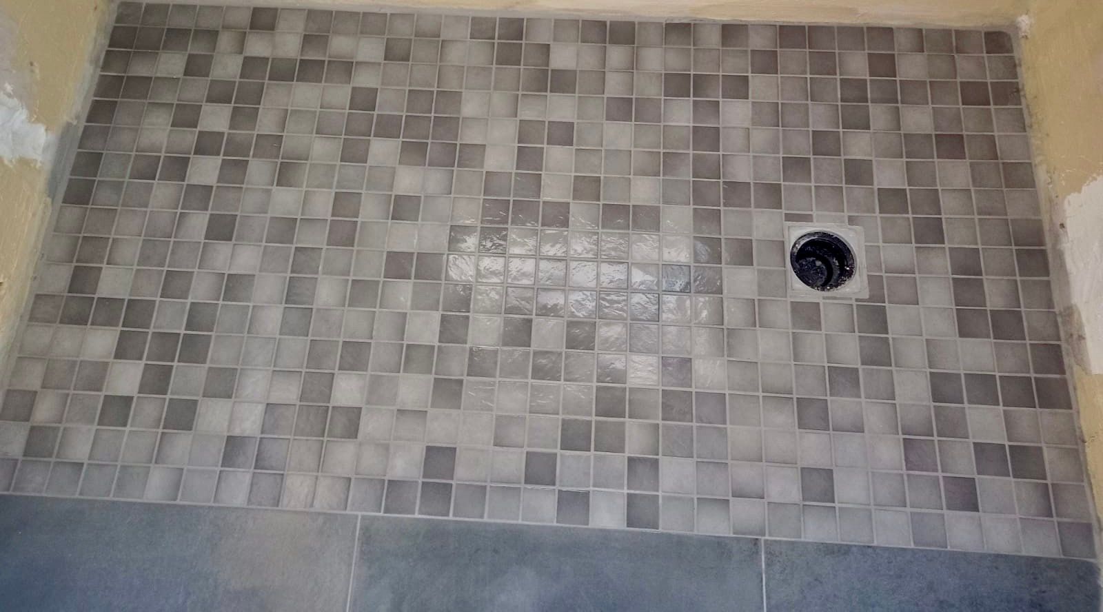 Un sol de douche orné d'une mosaïque grise