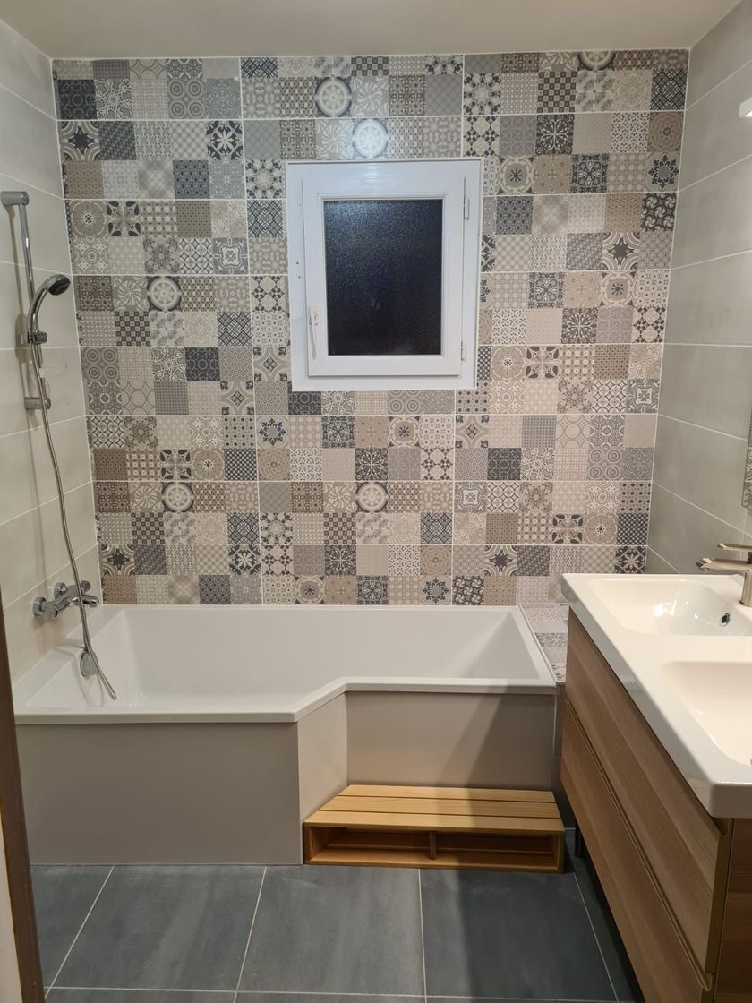 Salle de bain accessible avec baignoire, barre d'appui, marchepied, mur carrelé et lavabo