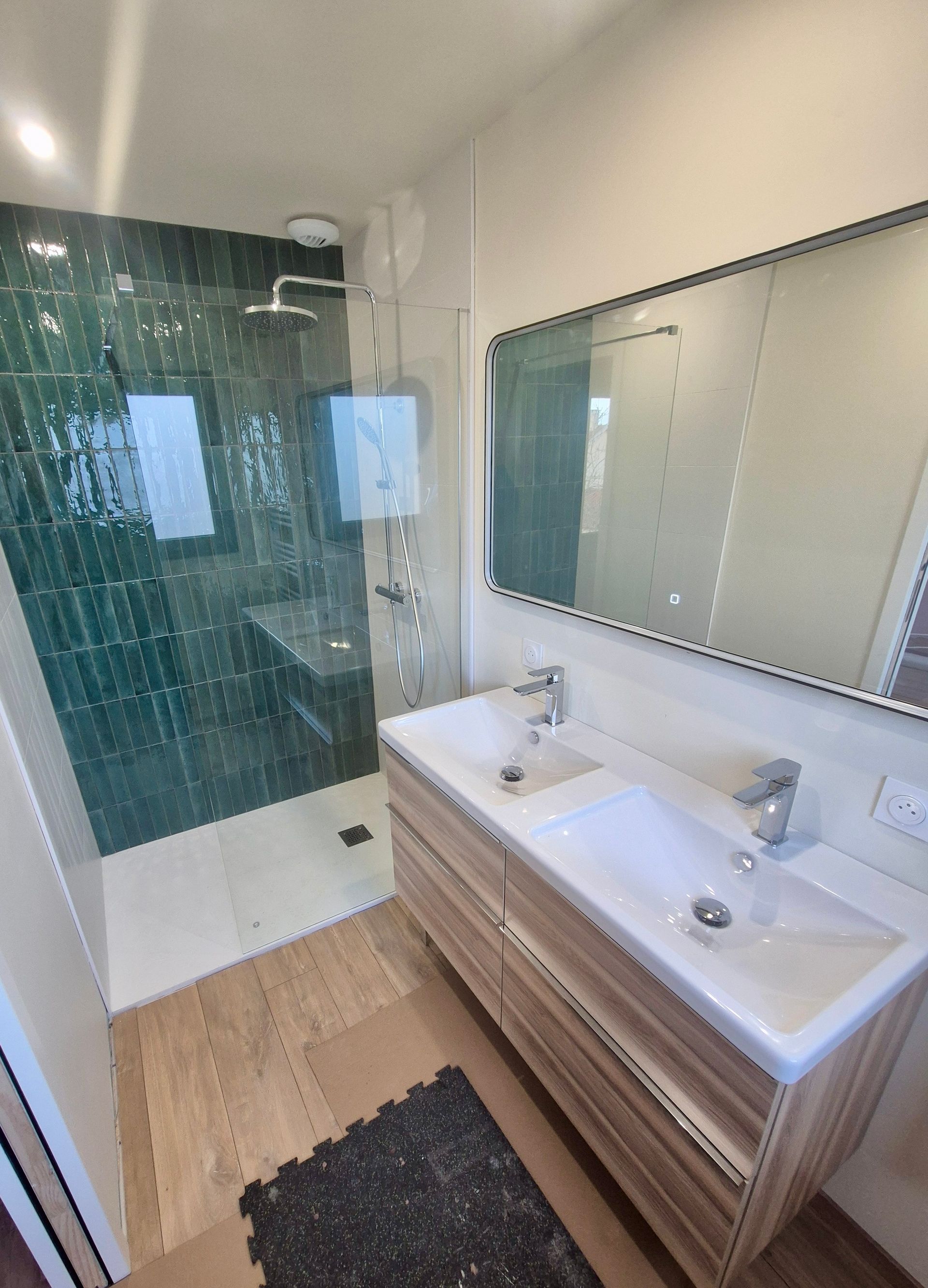 Une salle de bains moderne avec double vasque, miroir et douche à l'italienne avec des murs carrelés