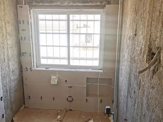 Baño en construcción con ventana y montantes de pared a la vista.