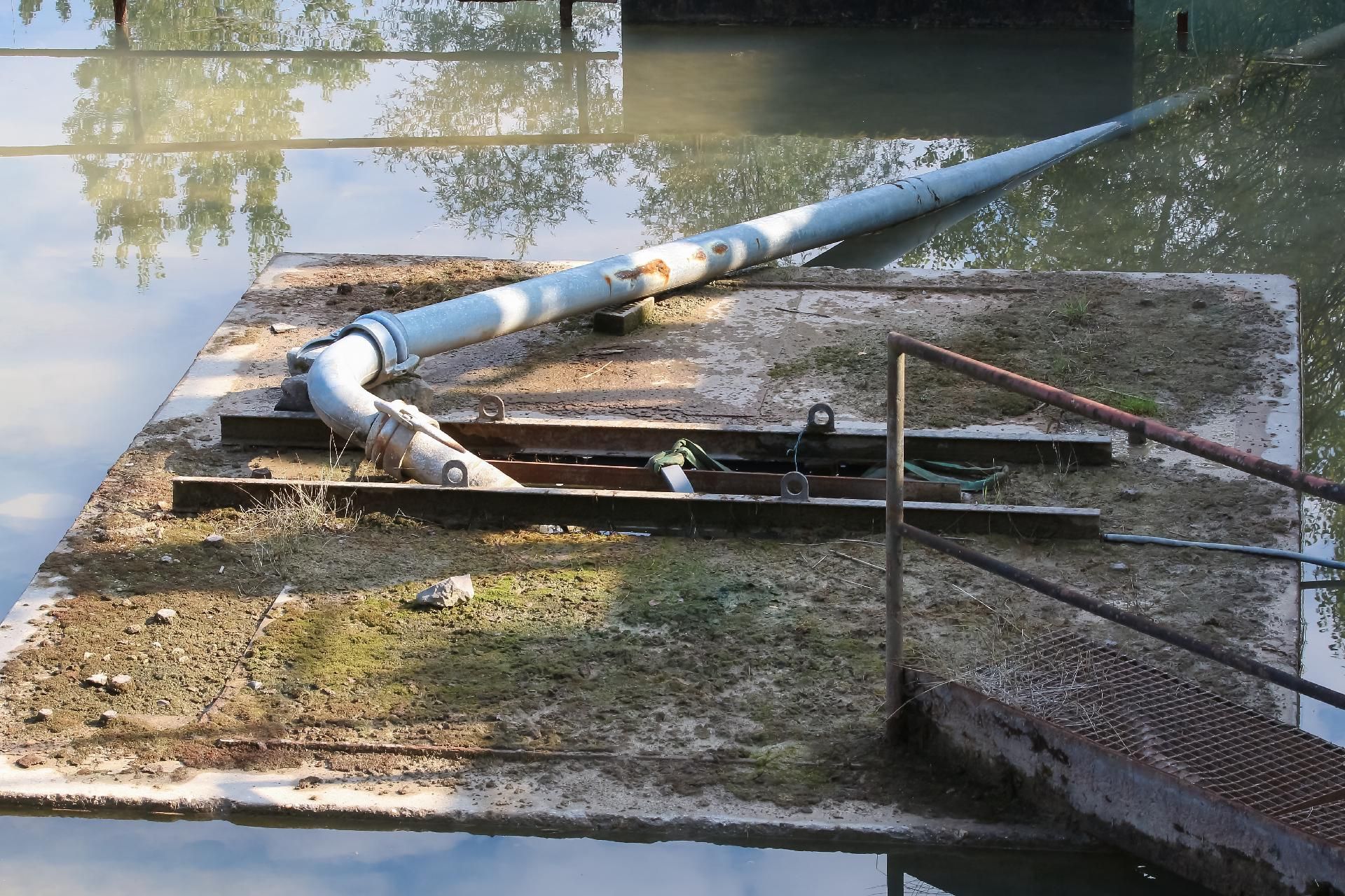 Eine überflutete, gebrochene Wasserleitung liegt über dem Wasser, umgeben von Trümmern 
