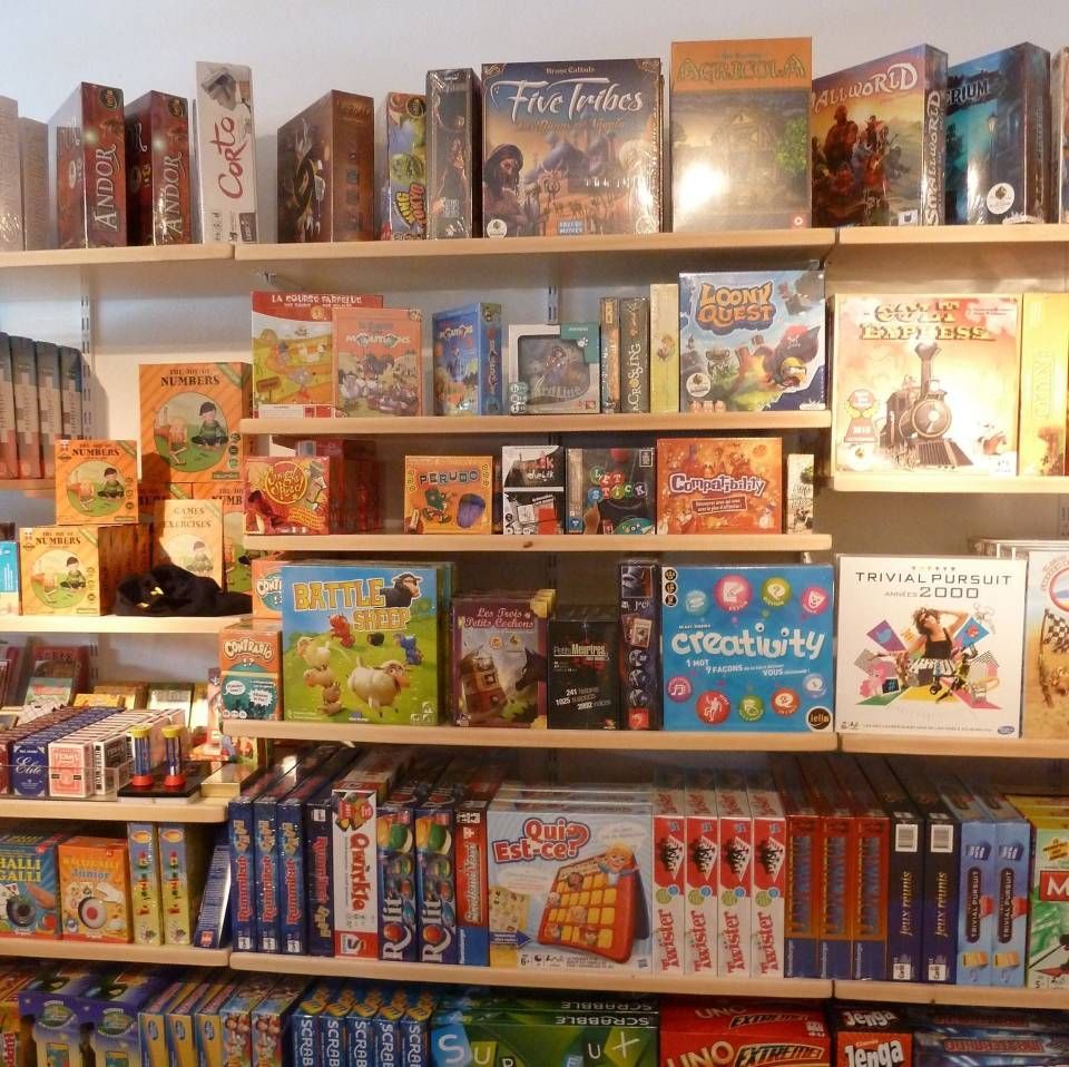 Des étagères remplies de jeux de société et de puzzles colorés dans un rayon de magasin de jouets