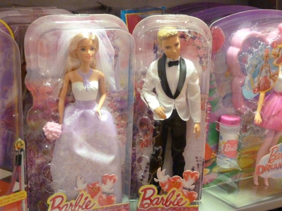 Trois poupées Barbie dans un emballage rose, dont une poupée mariée blonde et une poupée en smoking.